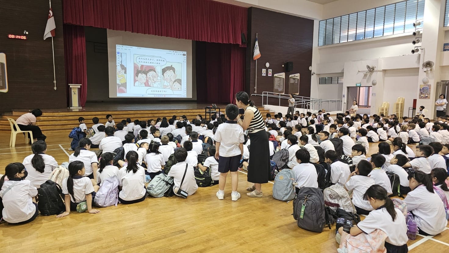 Captivated by the big screen, students gather in the hall for an engaging storytelling session that brings digital narratives to life.